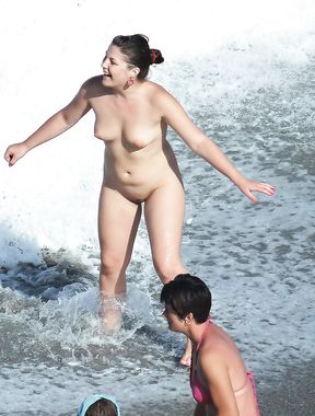 Naturist girl on a naked beach takes off her bra 2