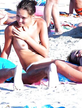 En una toalla con braguita blanca entre bañistas al sol