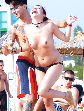 Two Adults on a Topless Beach with Thatched Umbrellas